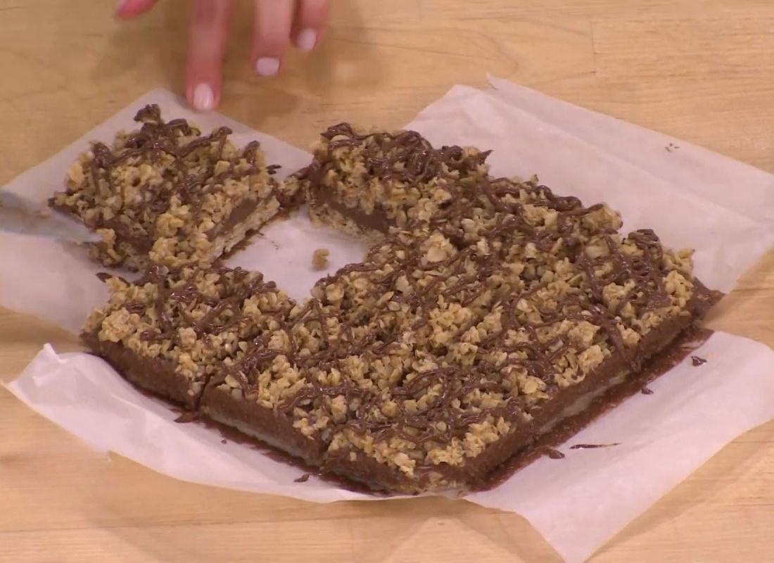 devojka seče kolač od ovsenih pahuljica i kikirikija