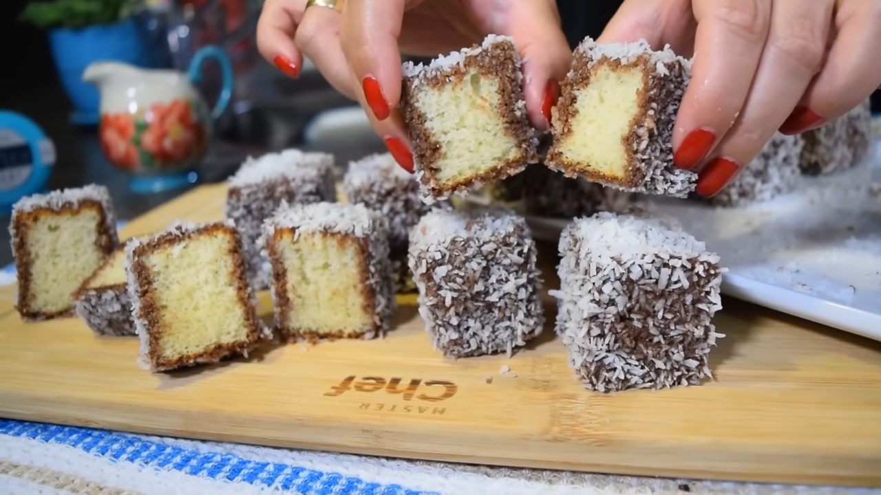 Čupavci sa kokosom umočeni u čokoladu i uvaljani u kokos, isečeni na kocke i servirani na dasci