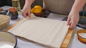 Ruke razvlače kore za baklavu na dasci