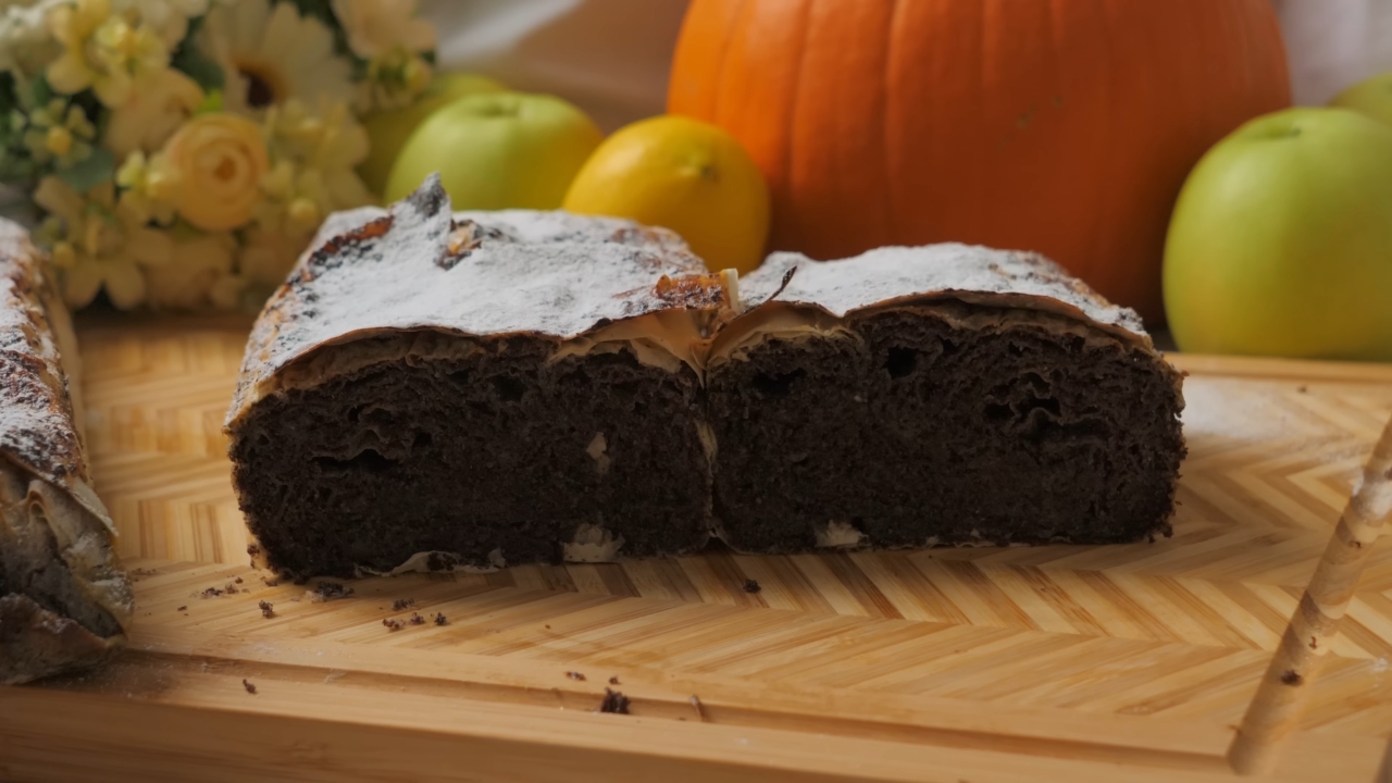 Domaća pita sa makom presečena na polovinu, servirana na drvenoj dasci