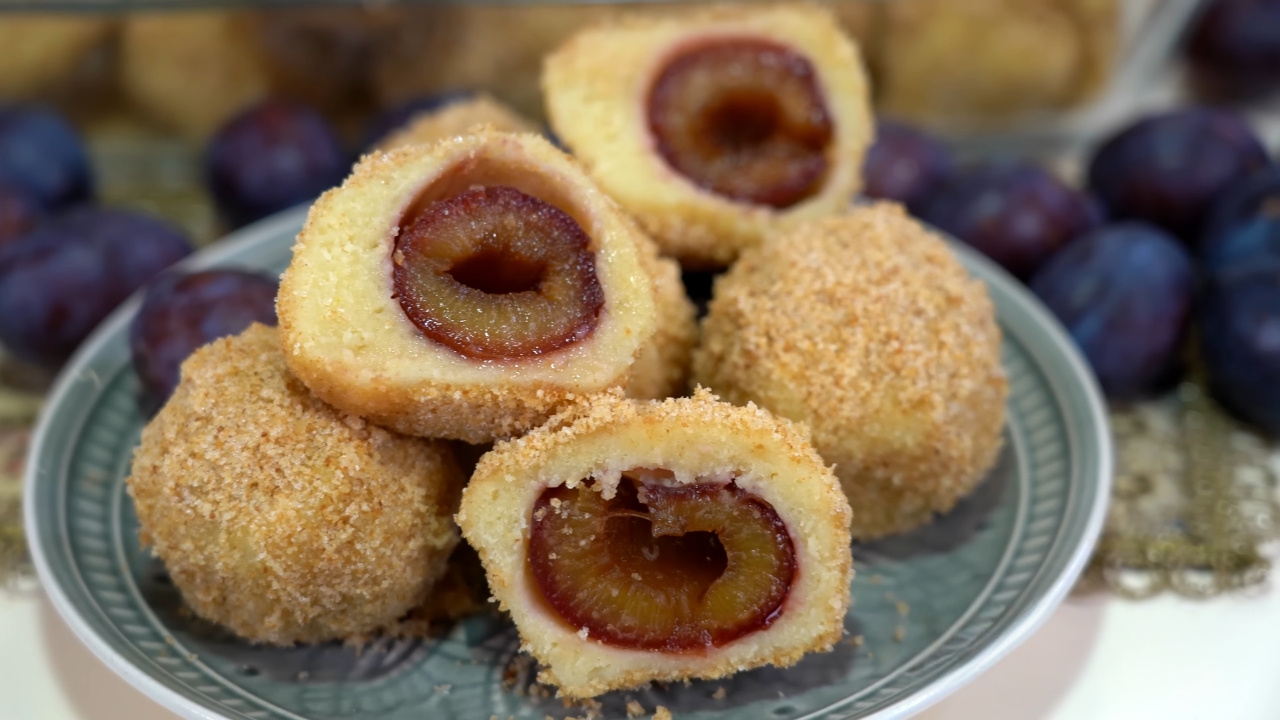 Domaće knedle sa šljivama presečene na pola i uvaljane u prezle na tanjiru