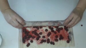 Uvijanje kore sa višnjama u čvrst rolat spreman za pečenje