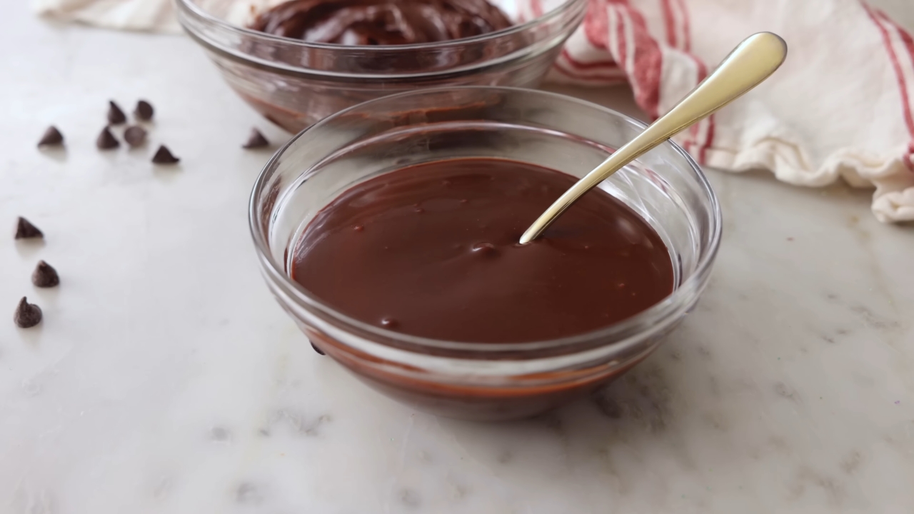 Sjajni ganaš od čokolade stoji u činiji spreman za prelivanje ili serviranje