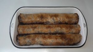 Zlatno pečeni rolati pite sa višnjama složeni u plehu, spremni za serviranje