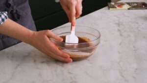 Osoba meša ganaš u činiji dok se sastojci sjedinjuju u glatku masu