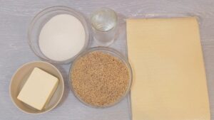 Sastojci za rozen tortu u činijama: šećer, orasi, maslac, kore i voda