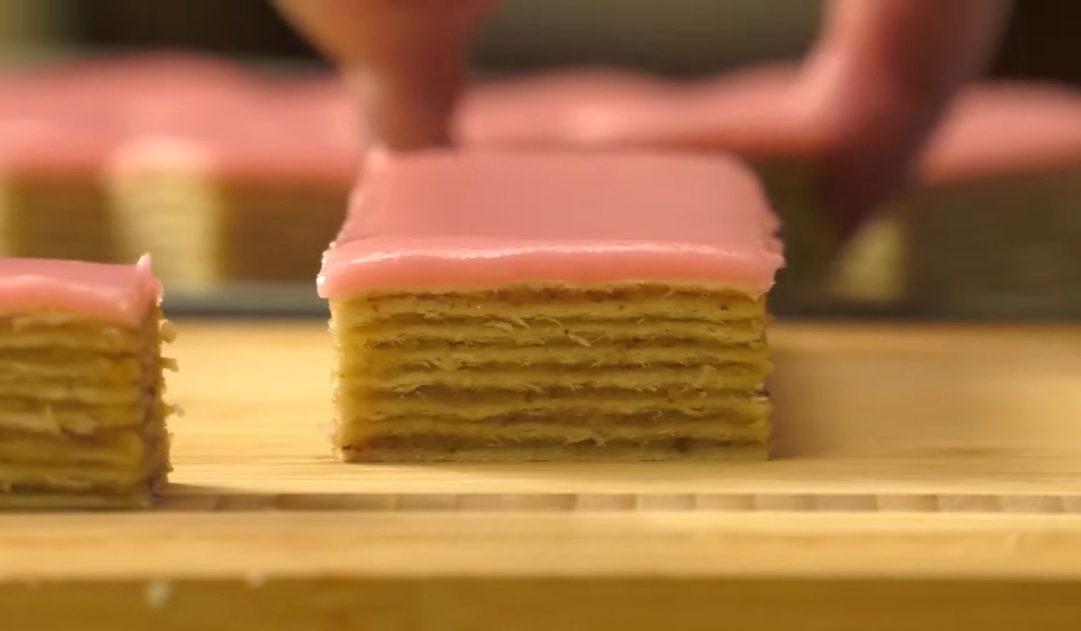 Parče rozen torte sa tankim slojevima i roze glazurom