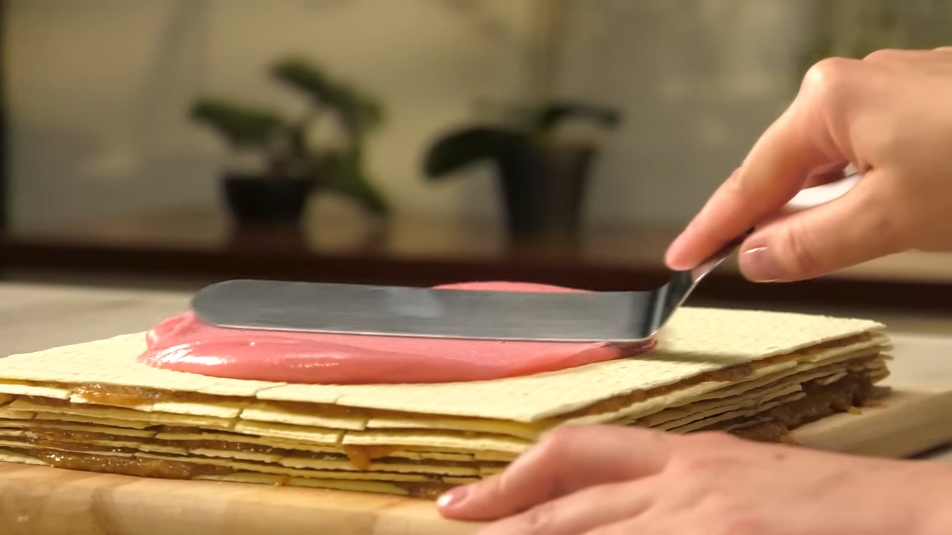 Mazanje roze glazure preko slojeva rozen torte