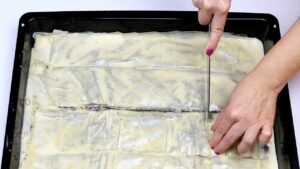 Pita je isečena na jednake kocke u tepsiji pre pečenja