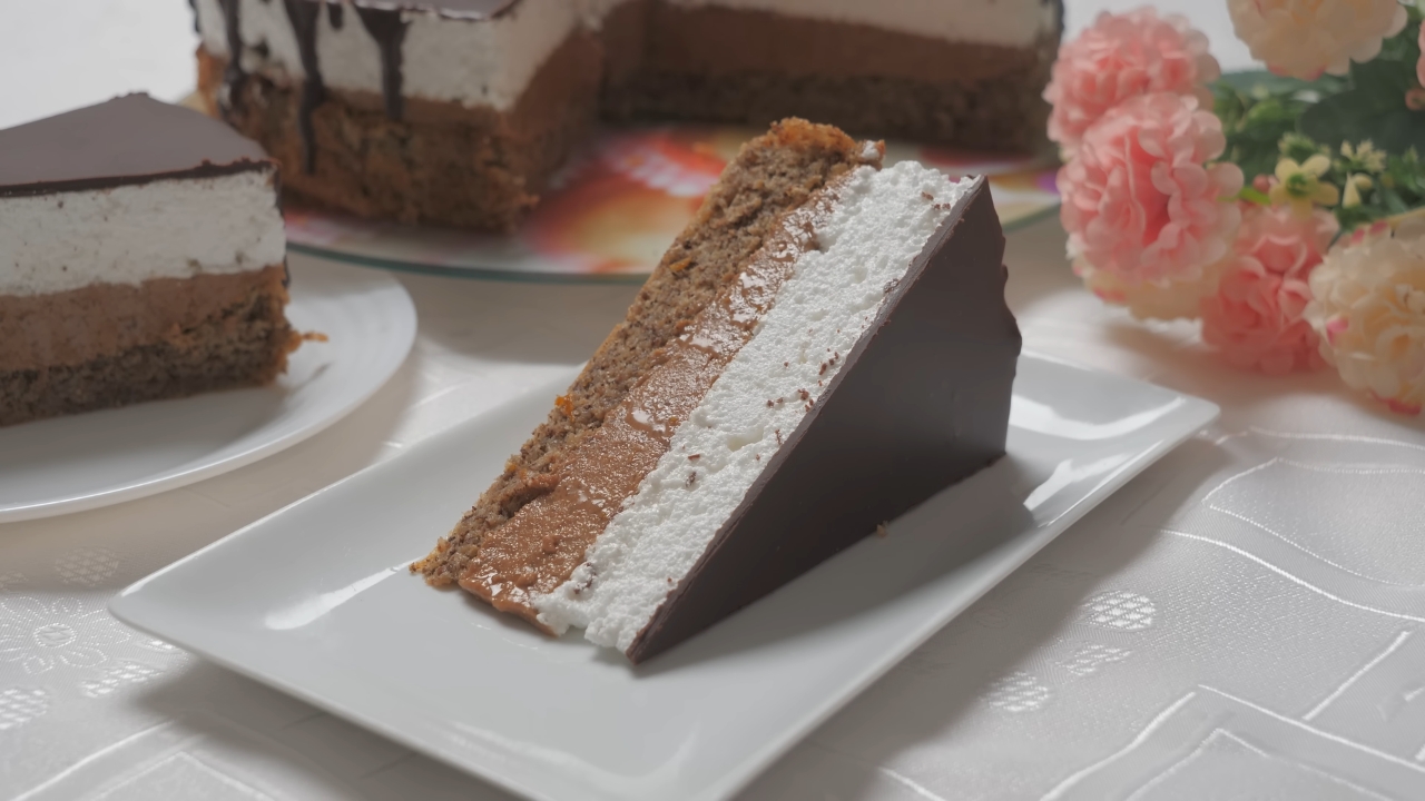 Parče Vasine torte sa slojevima oraha, kreme i čokoladne glazure na tanjiru