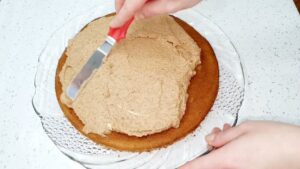 Ravnomerno nanošenje krema od oraha i čokolade preko ohlađene kore Vasine torte