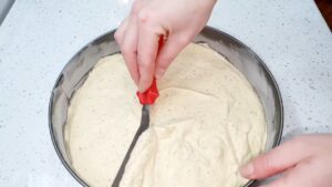 Ravnomerno raspoređivanje svetle smese za koru Vasine torte u okruglom kalupu